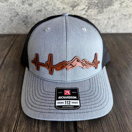 Heartbeat mountain leather patch hat on rustic wood background