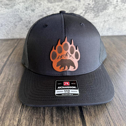 Black Richardson 112 hat with bear claw leather patch on rustic background