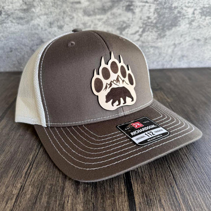 Close-up of hand-colored bear paw and mountain scene on leather patch