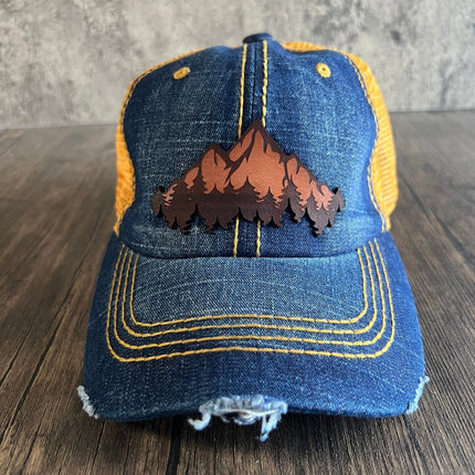Front view of denim and orange unstructured cap with leather mountain patch