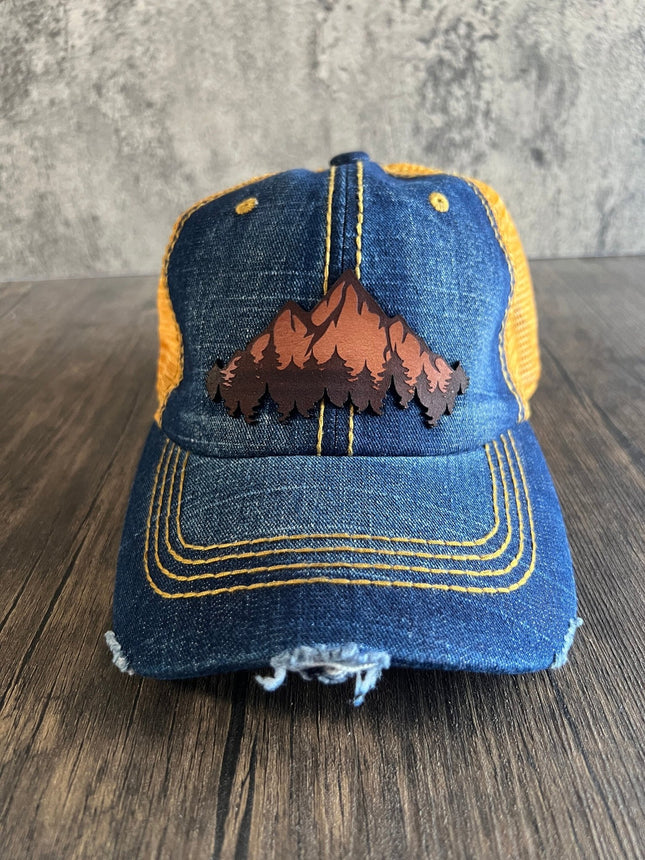Front view of denim and orange unstructured cap with leather mountain patch